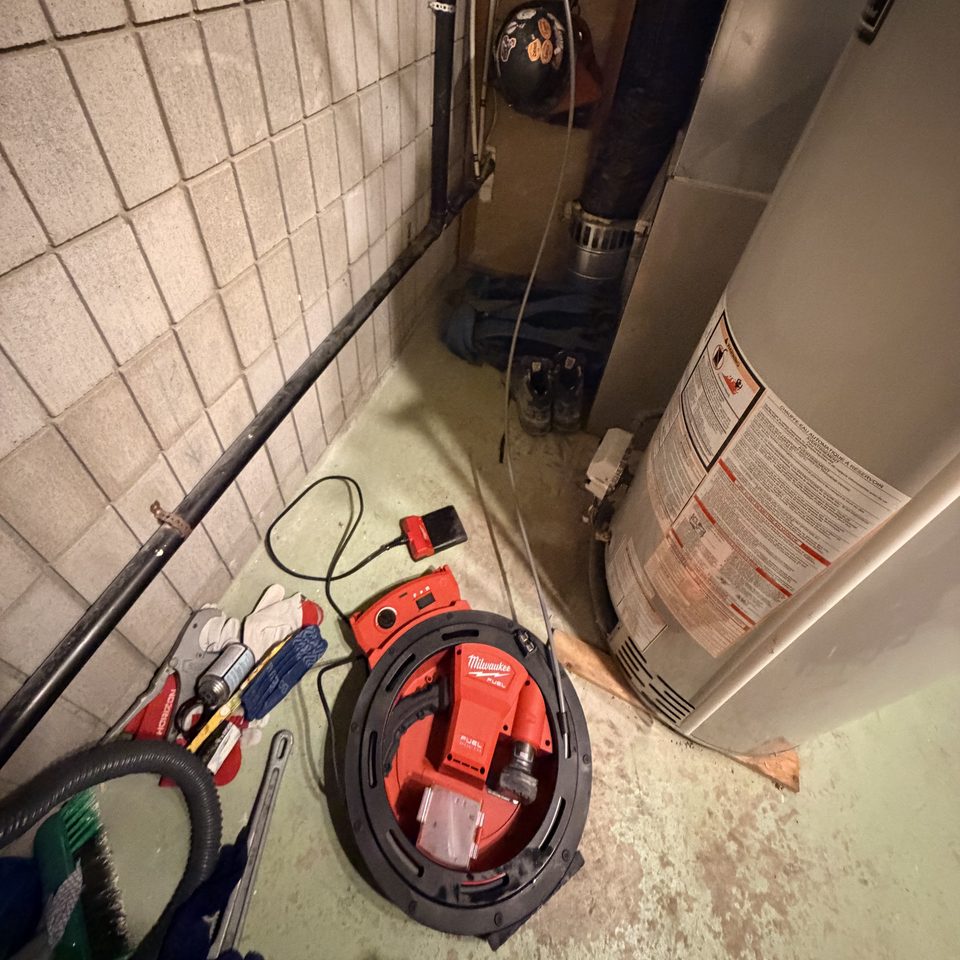Drum drain auger on a basement floor beside the water heater